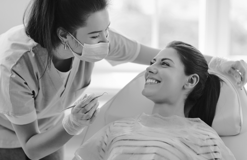 Dentist and a patient on a dentist chair smiling to each other
